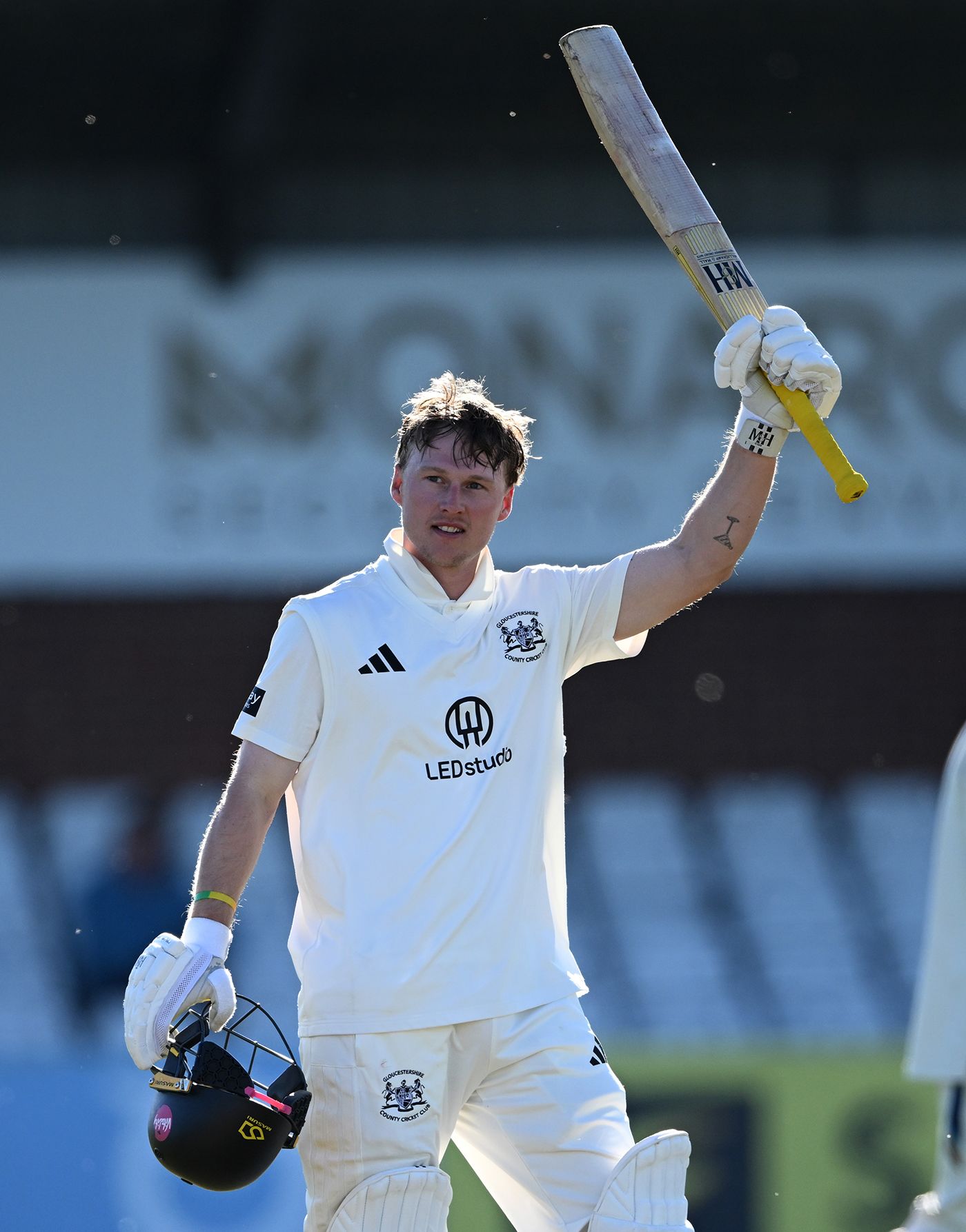 Miles Hammond raises his bat on reaching a century