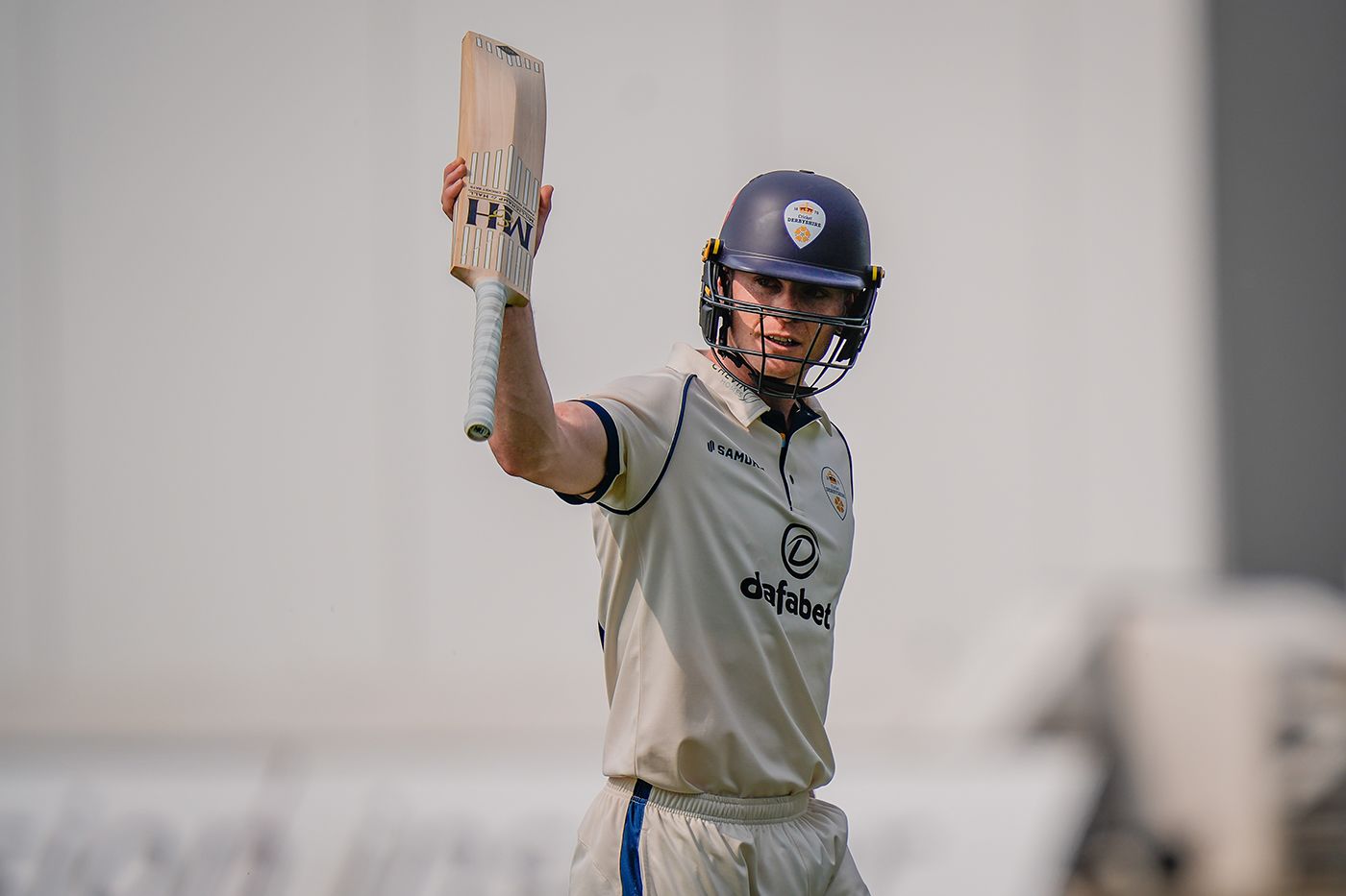 Brooke Guest raises his bat to salute the crowd after scoring a hundred