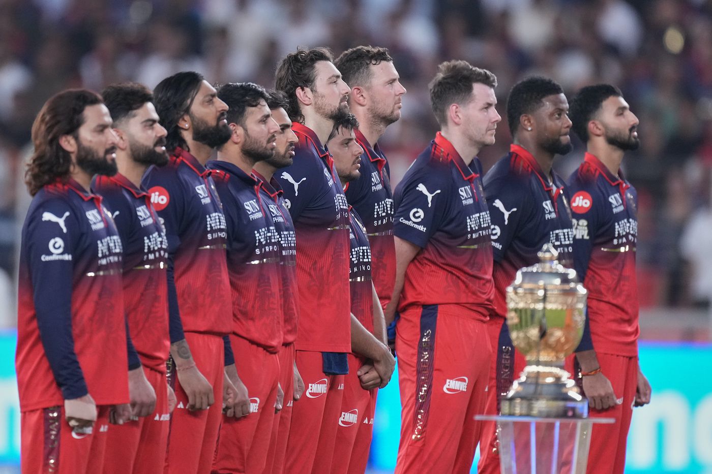 RCB players stand alongside the trophy during the National anthem