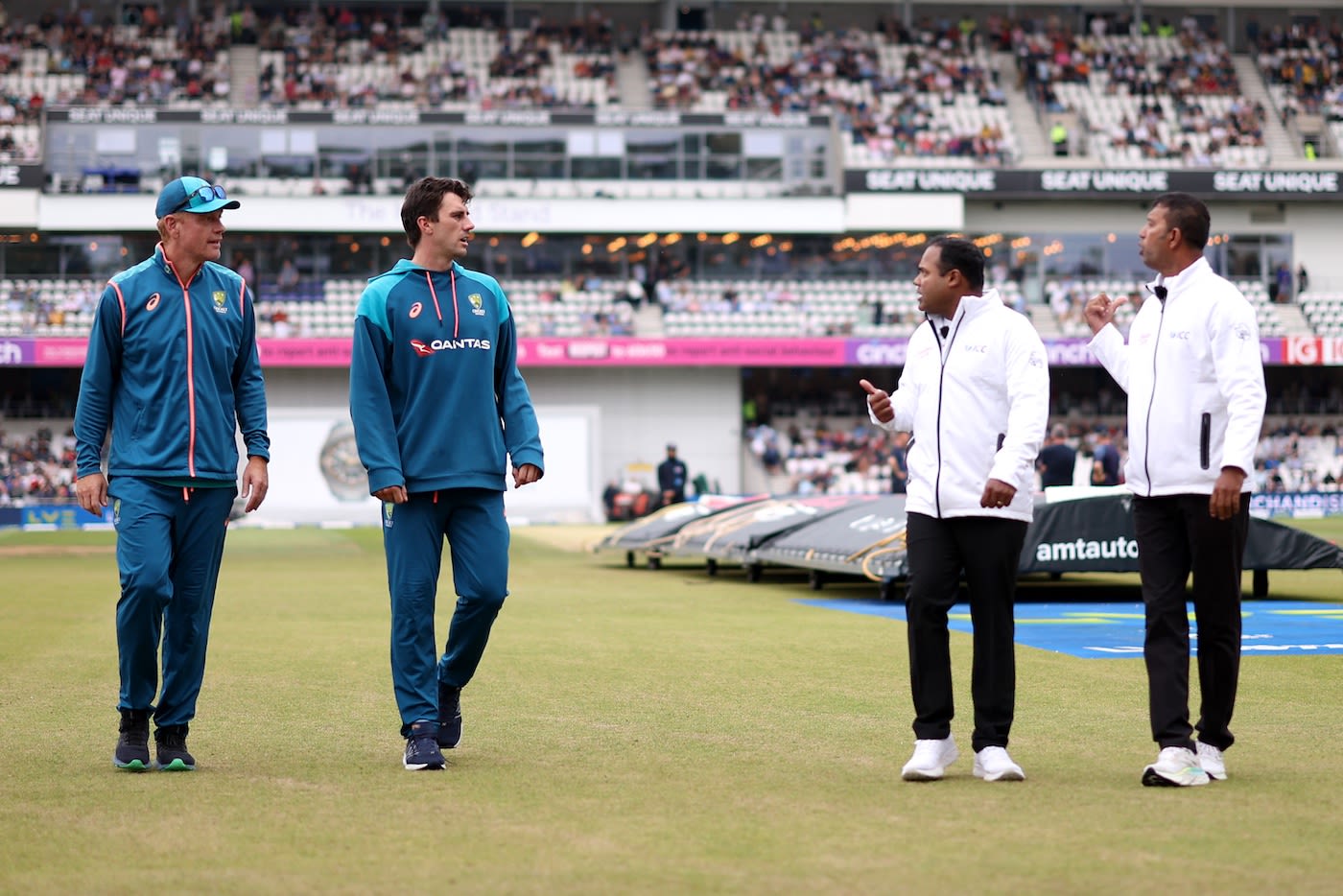 Andrew McDonald and Pat Cummins chat with Nitin Menon and Kumar Dharmasena during the rain delay
