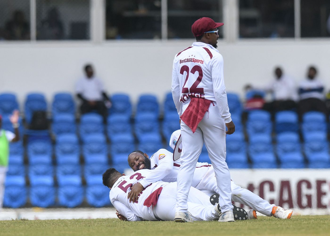 Jomel Warrican slides down towards Brandon King to celebrate Babar Azam's run out