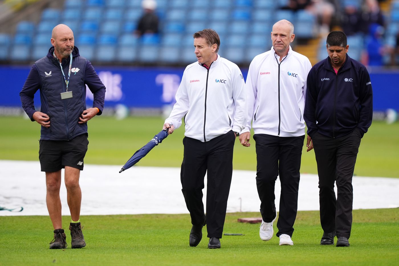 The umpires chat to groundstaff after heavy rain