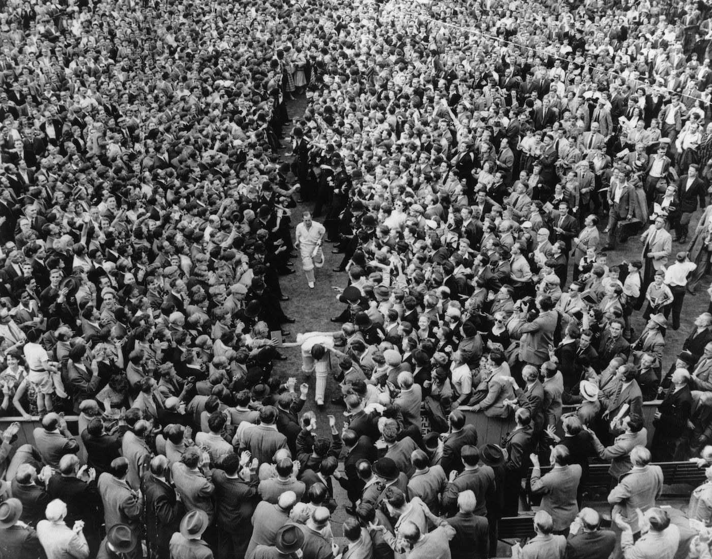 Denis Compton and Bill Edrich run off the ground to escape a swarming wave of fans