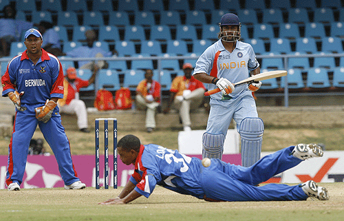 Bermuda bowler Lionel Cann tries to stop a shot off Mahendra Singh Dhoni