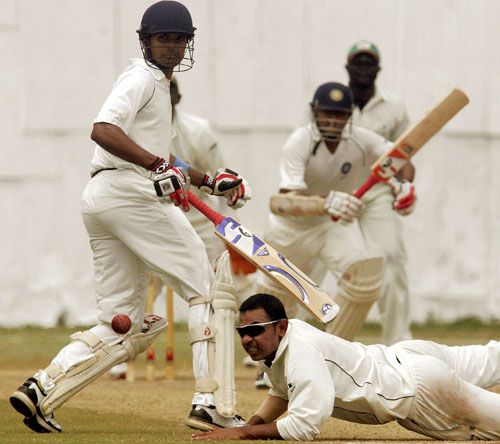 Parthiv Patel drives the ball past Hiren Varaiya as Subramaniam Badrinath looks on
