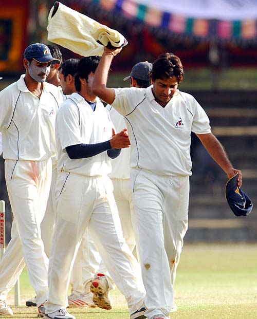 Mohammad Aslam leads his team off the field after Karnataka were bowled out for 329