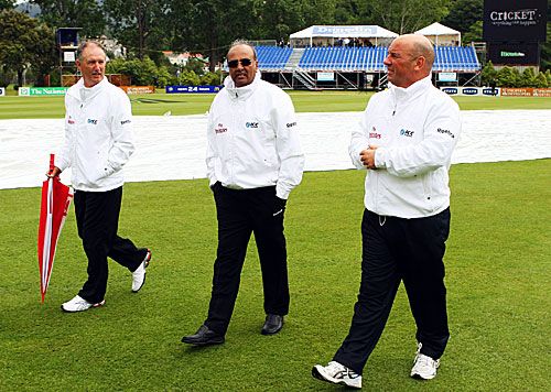 Umpires Tony Hill, Amiesh Saheba and Mark Benson inspect the wet outfield