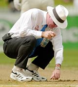Russell Tiffin inspects the deteriorating pitch