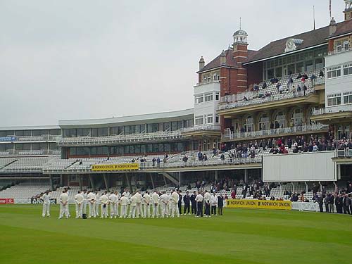Players from Surrey and Sussex gather for two minutes silence in front of The AMP Oval Pavilion.
