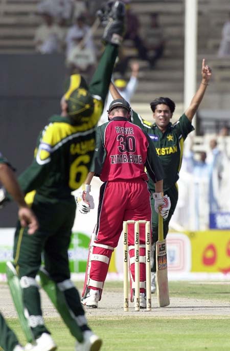Rashid Latif (L) celebrates his catch of Zimbabwe batsman Gavin Rennie (C)