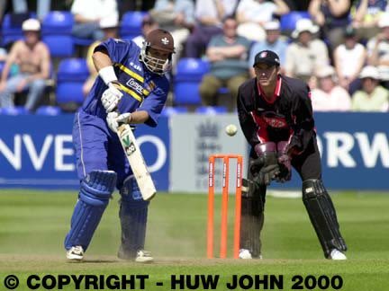 Mark Butcher hits a boundary watched by Adrian Shaw