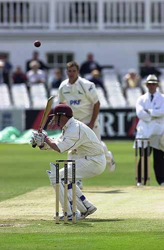 Greg Smith bounces a ball past the Northants century maker Tony Penberthy