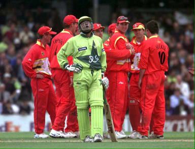 Pakistan batsman Moin Khan walks off as the Zimbabwe team celebrate his runout