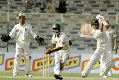 Yasir Hameed (R) hits a ball as wicketkeeper Khaled Mashud (L) and fielder Sanwar Hossain (C) look on during the fourth day of the first Test match between Pakistan and Bangladesh in Karachi