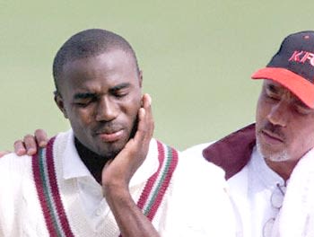 Kerry Jeremy holds his broken jaw as Dujon accompanies him back
