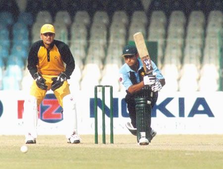 Naumanullah drives a ball as Moin Khan looks on
